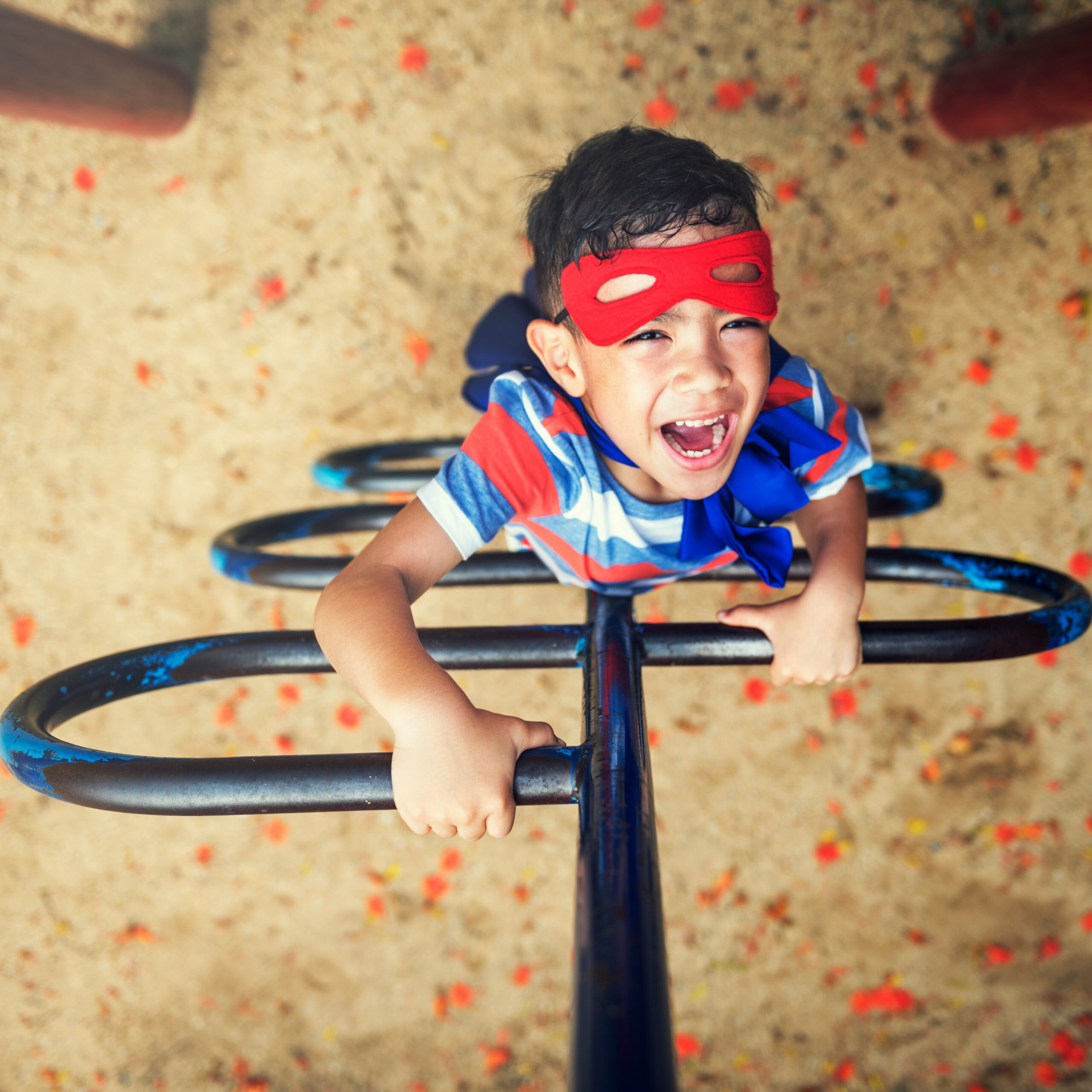 A elementary age child climbing a ladder with a super hero mask on.