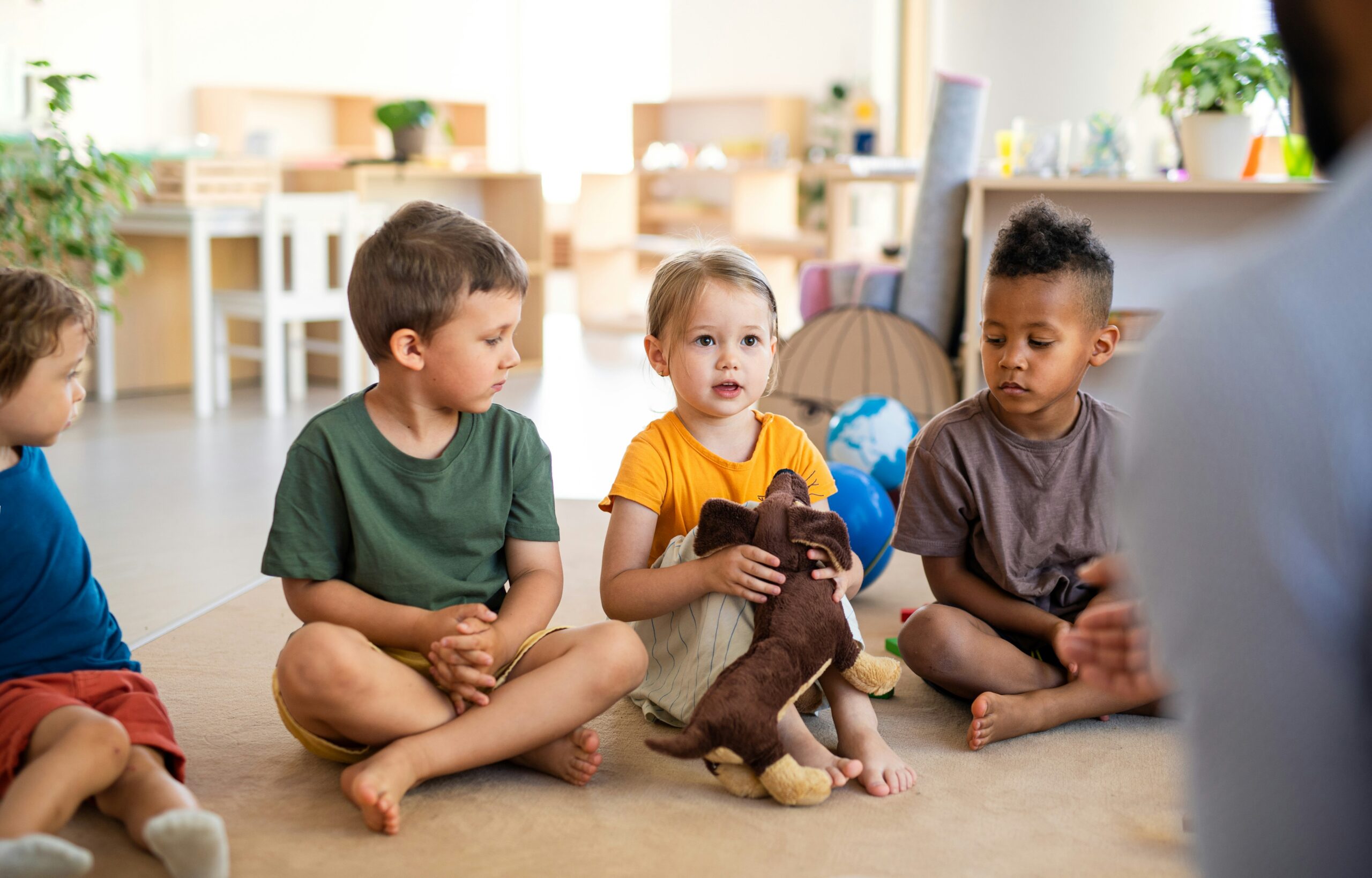 young children sitting in circle time in a classroom.